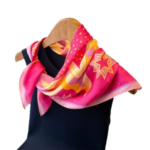 Vintage geometric print silk scarf in vibrant pink draped on a wooden hanger with a black top