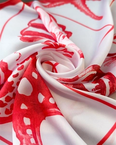 Detail of silk scarf with red starfish prints and glossy satin texture in rose fold