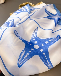 Close-up of silk scarf fabric showing blue starfish print and glossy satin texture
