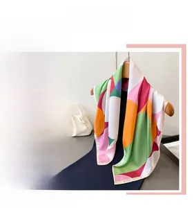 Detail of colorful geometric print silk scarf with smooth satin finish on wooden hanger