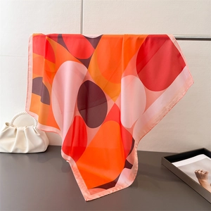 Modern geometric silk-like square scarf draped on a metal bar with chic accessories