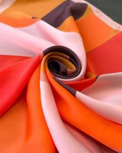 Macro detail of silk square scarf showing satin luster and warm geometric abstract patterns