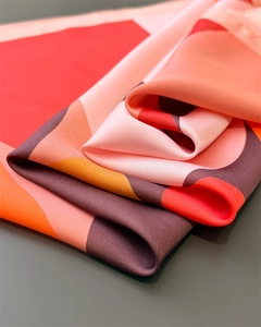 Close-up of silk scarf with red wavy patterns showing soft texture and satin luster