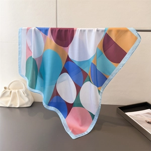 Close-up of geometric pattern silk scarf draped on metal rod with pearl handle bag