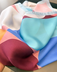 Close-up of geometric pattern silk scarf showing satin texture and rolled edge detail