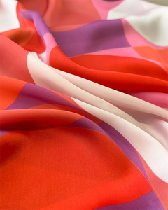 Macro detail of silk scarf showing vibrant geometric patterns and smooth fabric texture