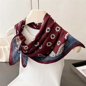Dettaglio di sciarpa in seta bordeaux con stampe di margherite e bordi paisley