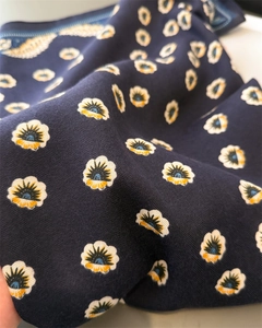 Dettaglio del tessuto a spina di pesce blu navy con piccole stampe di girasoli arancioni