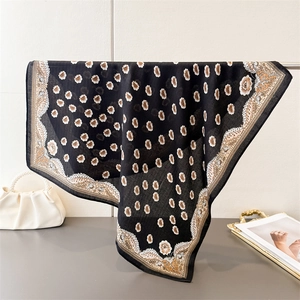 Dettaglio di foulard quadrato con stampa floreale appeso accanto a borsa con perle