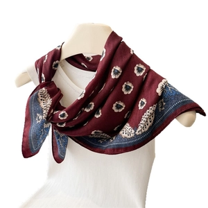 Elegante sciarpa in seta bordeaux con fiori e bordo paisley su busto di manichino