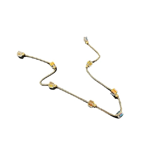 Minimalist gold titanium necklace with amber crystal cubes on a white surface