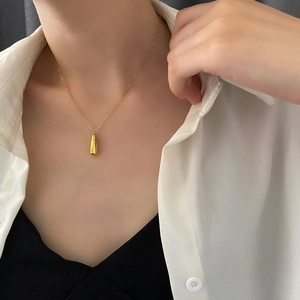 Collier avec pendentif flacon de parfum doré poli sur mannequin en acier titane élégant