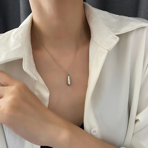 Collier minimaliste en acier titane argenté flacon de parfum sur chemise blanche