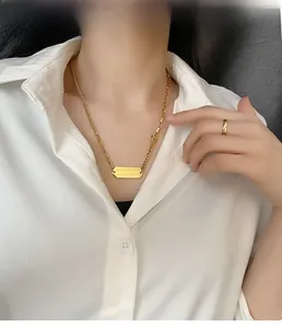 Detail of gold layered necklace with rectangular pendant worn on a white shirt