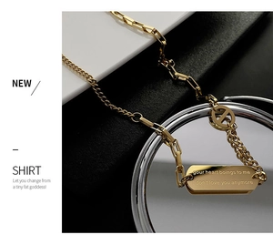 Close-up of gold titanium necklace featuring H pendant and engraved rectangular tag