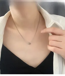Close-up of minimalist silver twisted knot pendant necklace on a female neck