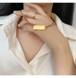 Detail showing gold rectangular pendant with meaningful engraving on white shirt