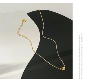Close-up of minimalist gold titanium necklace with mirror-finish geometric pendant