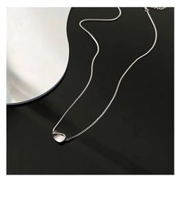 Macro shot of liquid metal irregular pendant on a silver box chain over black background
