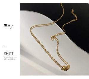 Detail of a gold titanium geometric twisted pendant on a delicate box chain necklace