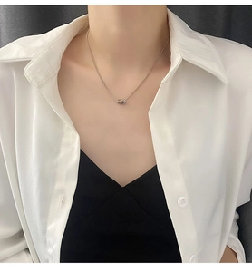Detail shot of a silver titanium geometric pendant necklace worn on a white shirt