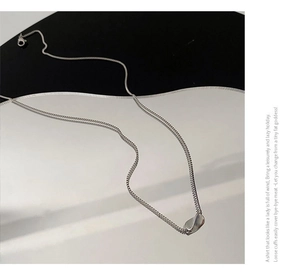 Macro detail of a silver geometric twisted pendant on a delicate box chain necklace