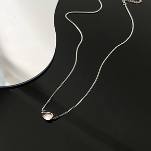 Minimalist silver geometric necklace with an organic shaped pendant on a black background