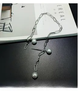 Close-up of silver long link chain necklace with three white pearls on a magazine
