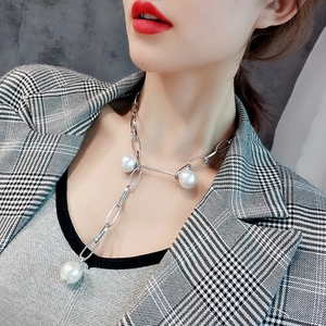 Detail of silver long pearl necklace with Y-shaped geometric clasp and large white pearls