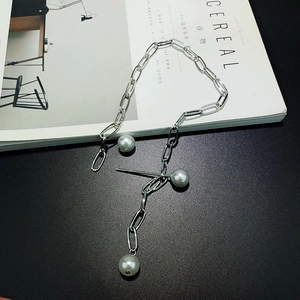 Close-up of silver paperclip chain necklace featuring three elegant white pearls