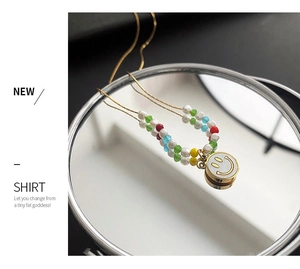 Detailed close-up of colorful beaded necklace with a golden smiley face charm on a mirror