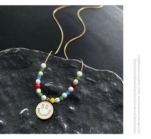 Detail of colorful beads and enamel smiley face pendant on a golden chain necklace