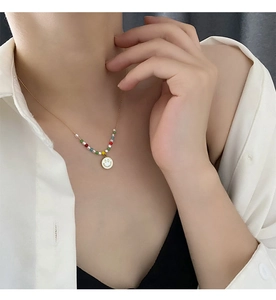 Detailed shot of multi-color beads and smiley face pendant on a gold titanium steel necklace