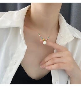 Close-up of minimalist titanium steel necklace with colorful beads and white smiley pendant