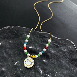 Colorful beaded smiley face necklace with gold chain on dark textured background