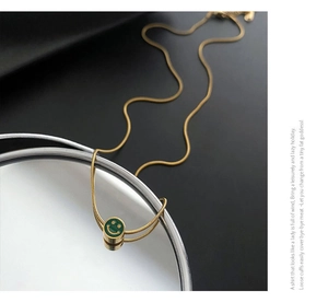 Detalle de un collar de cadena de serpiente dorada con colgante de cara sonriente