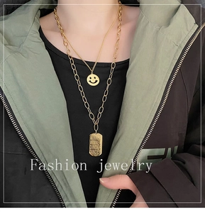 Detail view of double-layer gold necklace with smiley face and engraved winner tag