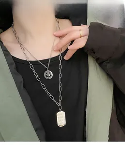 Detail of layered titanium steel necklaces featuring a smiley face and engraved dog tag