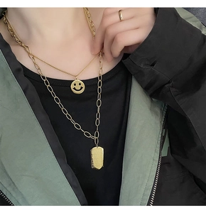Close-up of double-layer gold titanium steel necklaces with smiley face and slogan tags