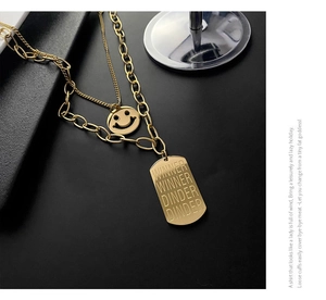 Macro detail of gold-plated double-layer necklace with smiling face and engraved plate