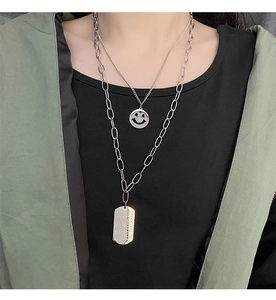 Close-up of double-layer stainless steel necklace featuring smiley face and engraved tags