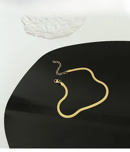 Detailed view of an 18K gold snake chain with lobster clasp and adjustable link on a stand