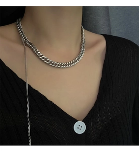 Close-up of silver Cuban link chain with long pendant on black V-neck knitwear