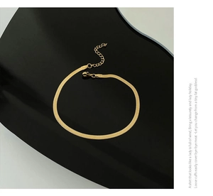 Detailed view of polished 18K gold snake bone chain anklet with lobster clasp closure