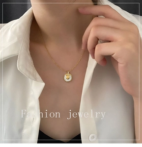 Détail d'un collier doré avec pendentif en nacre blanche et pierre de zircon scintillante