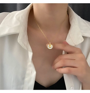 Gros plan d'un collier en titane doré avec pendentif en nacre porté par un mannequin