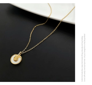 Détail de collier doré avec pendentif en nacre blanche et incrustation de la lettre B