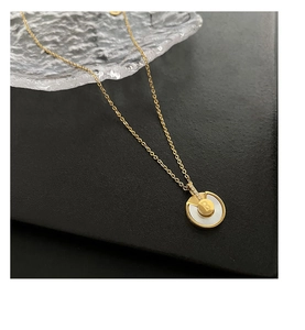 Détail du collier en titane doré avec pendentif en nacre et charm lettre B scintillant