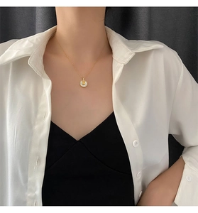 Gros plan d'un collier doré en titane avec pendentif en nacre porté par un modèle