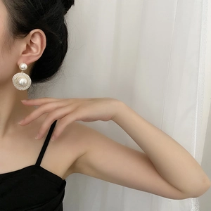 Gros plan de boucles d'oreilles perles avec anneaux de diamants pavés portées par un mannequin